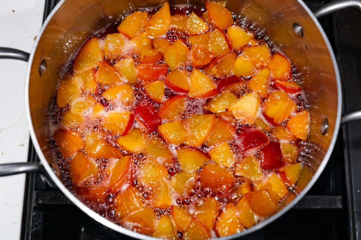 This is the absolute BEST fresh peach lemonade recipe! Sweet juicy peaches combined with tart, tangy lemons make the most refreshing drink. You will want to have a pitcher of this in your fridge throughout the peach season! Overhead shot of mixture boiling in a pot.