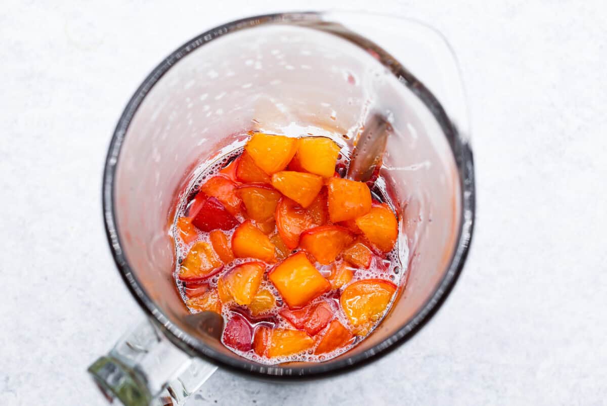 This is the absolute BEST fresh peach lemonade recipe! Sweet juicy peaches combined with tart, tangy lemons make the most refreshing drink. You will want to have a pitcher of this in your fridge throughout the peach season! Overhead shot of peach mixture in a blender.